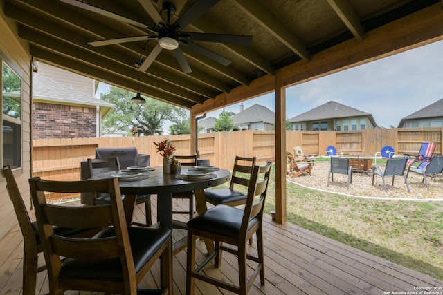 wooden deck featuring a fenced backyard, a ceiling fan, outdoor dining area, and a fire pit