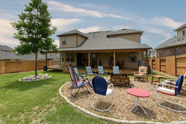 back of property featuring a fenced backyard, an outdoor fire pit, a yard, and a shingled roof
