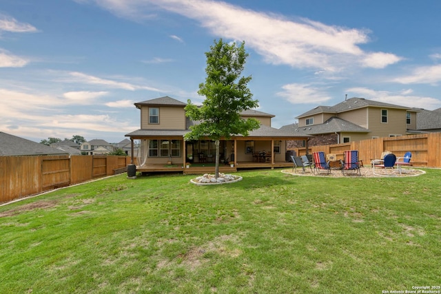 rear view of house featuring a lawn, a fenced backyard, a fire pit, and a wooden deck