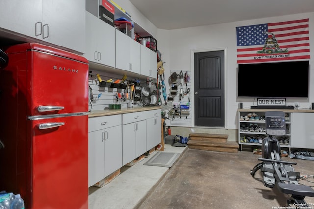 kitchen featuring freestanding refrigerator, concrete flooring, and white cabinetry