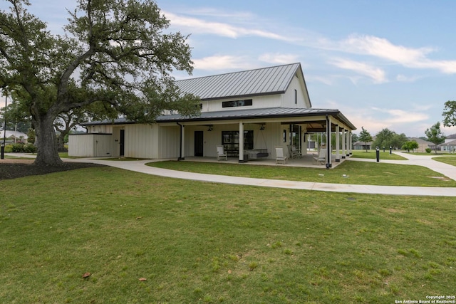 view of front of house with a front lawn, board and batten siding, a porch, concrete driveway, and metal roof
