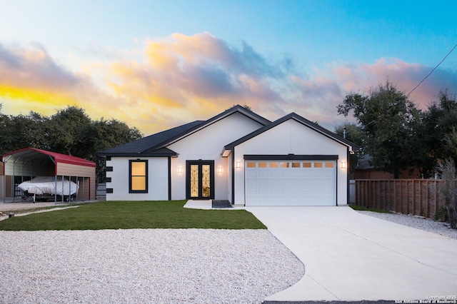 view of front of house with french doors, a detached carport, a garage, fence, and a yard