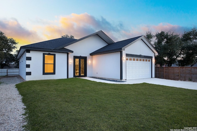 view of front of house with fence, an attached garage, concrete driveway, french doors, and a yard
