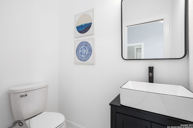 bathroom with baseboards, vanity, and toilet