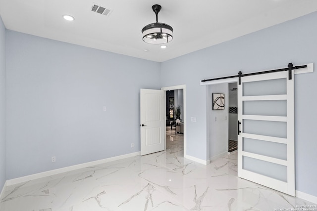 unfurnished bedroom with baseboards, a barn door, and visible vents