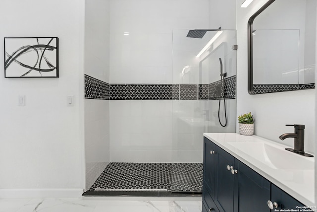 bathroom with baseboards, tiled shower, marble finish floor, and vanity