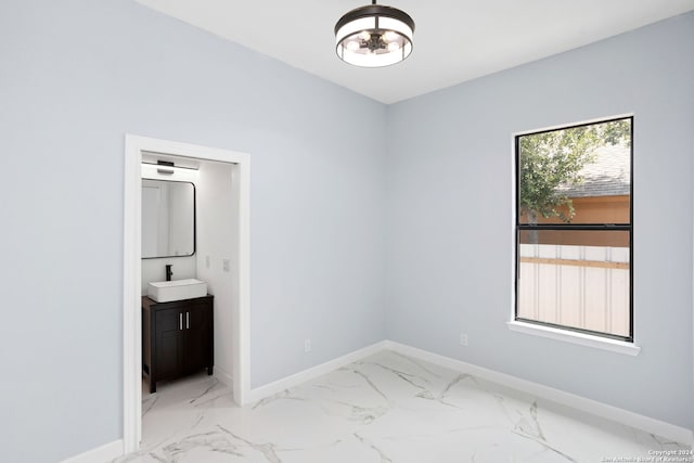 unfurnished bedroom featuring a sink, baseboards, a notable chandelier, and marble finish floor