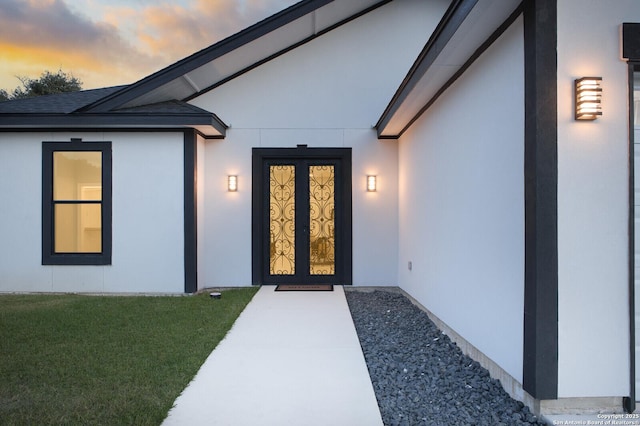 exterior entry at dusk featuring a yard and stucco siding