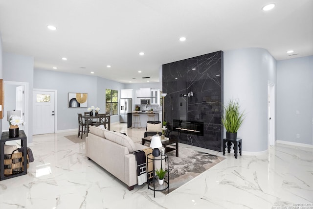 living area with recessed lighting, marble finish floor, and baseboards