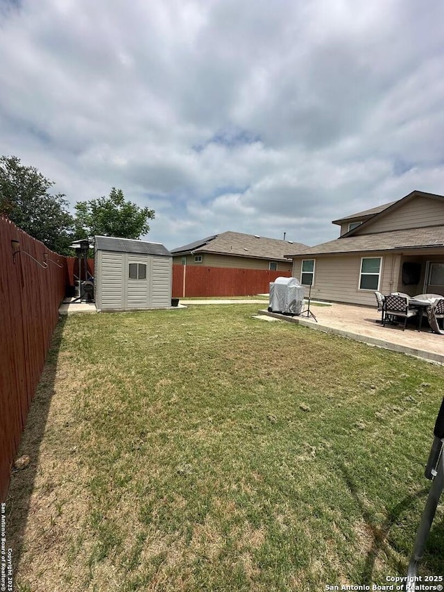 view of yard with an outbuilding, a fenced backyard, a patio area, and a storage unit