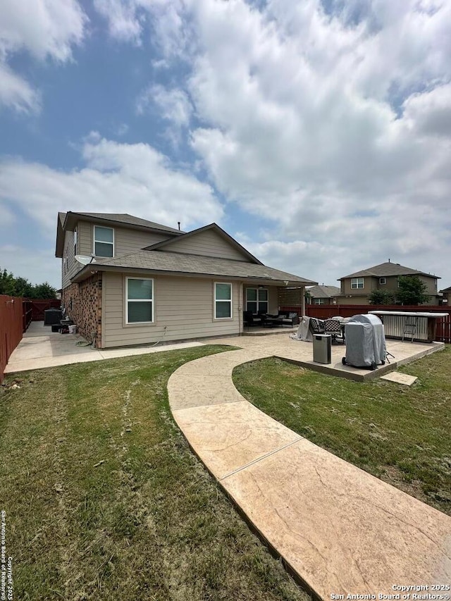 rear view of property with a lawn, a patio area, and fence