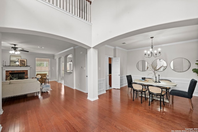 8715 Anton Chico, Helotes, TX 78023 - dining area with crown molding, a fireplace, ceiling fan with notable chandelier, and wood finished floors