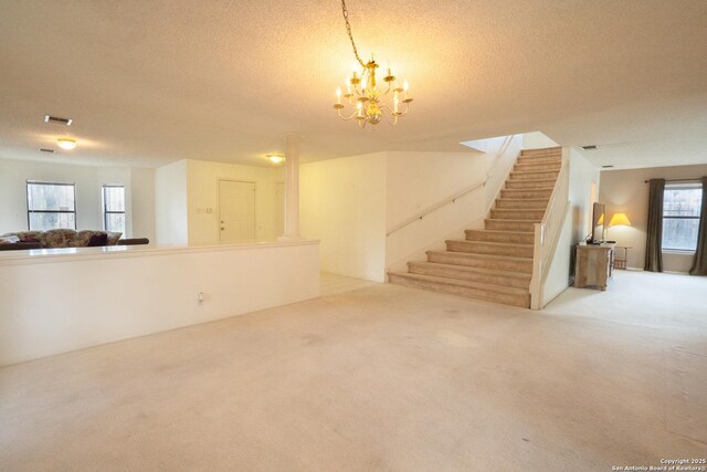 1903 Copperfield, San Antonio, TX 78251 - unfurnished living room with a textured ceiling, visible vents, stairway, a chandelier, and carpet flooring