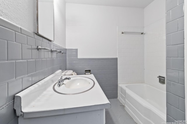 bathroom with shower / washtub combination, tile walls, wainscoting, and vanity