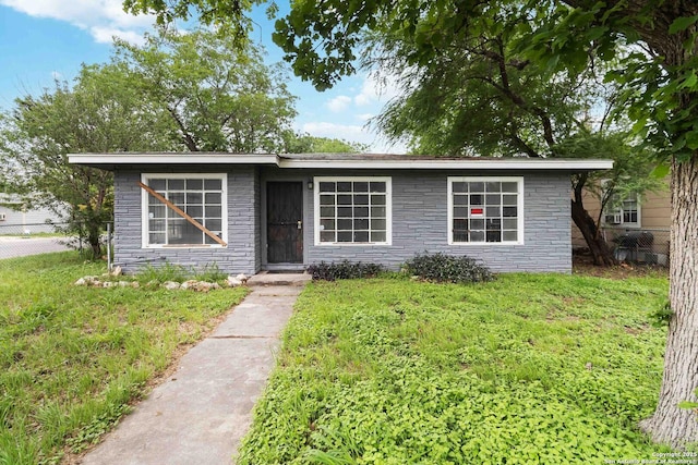 view of front of home featuring fence, stone siding, and a front yard