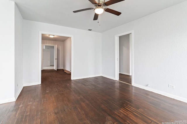 empty room with baseboards, a ceiling fan, wood finished floors, and visible vents