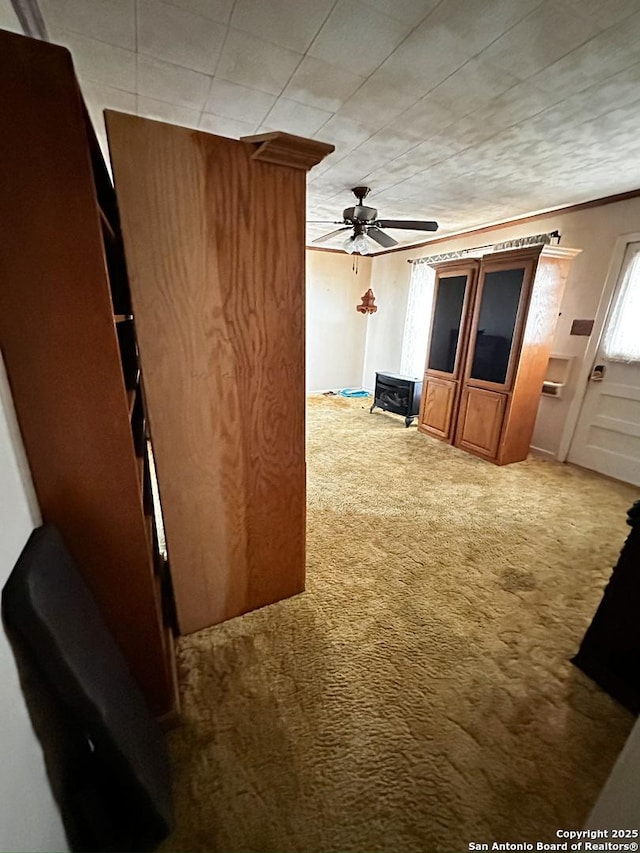 unfurnished living room with carpet floors, crown molding, and ceiling fan