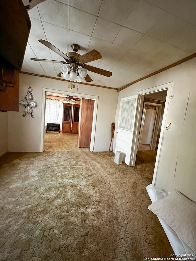 unfurnished dining area with carpet flooring, ceiling fan, and ornamental molding