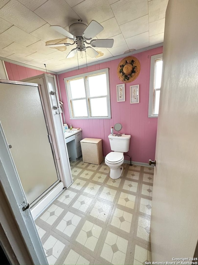 bathroom with a ceiling fan, tile patterned floors, toilet, and a shower stall