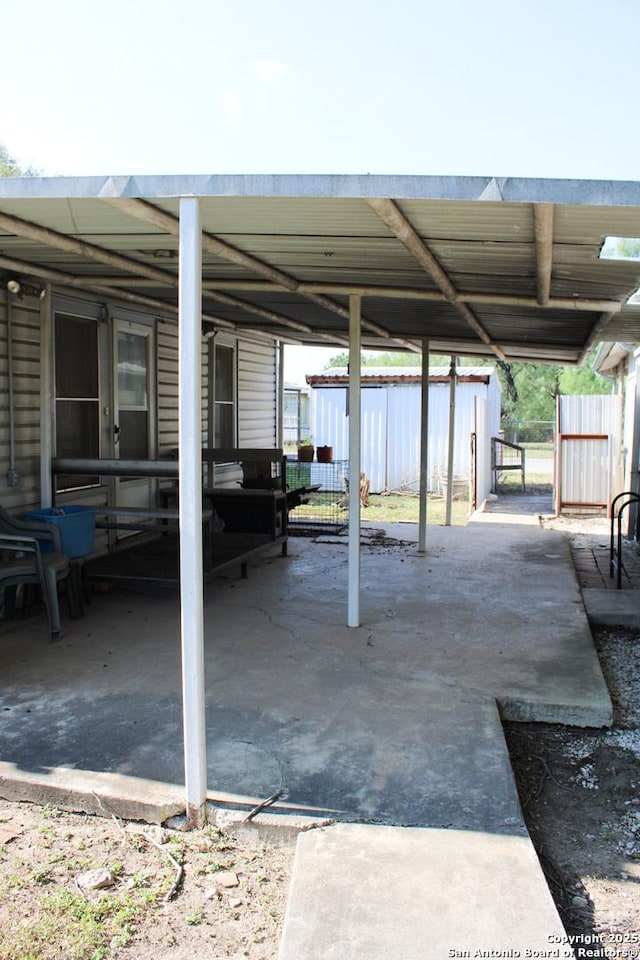 view of patio featuring an outdoor structure, fence, and a carport