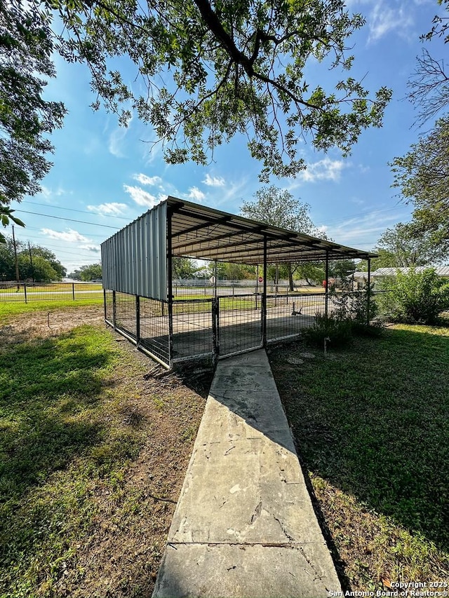 view of parking featuring fence and a carport