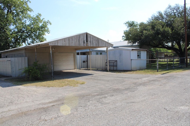 view of outbuilding featuring fence, an outbuilding, and driveway