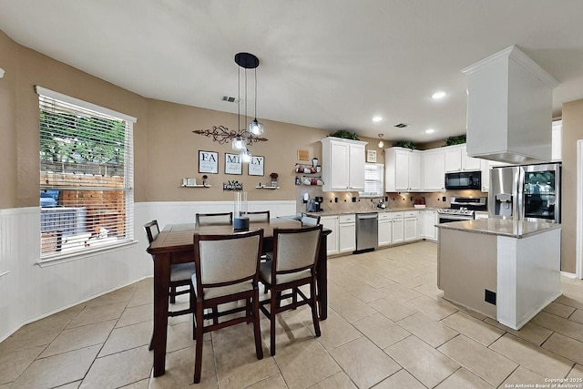 kitchen featuring wainscoting, light tile patterned floors, white cabinets, and stainless steel appliances