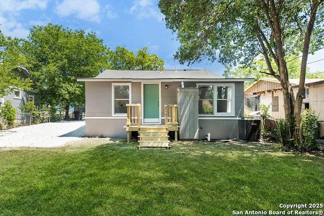 back of property with central air condition unit, a yard, and fence