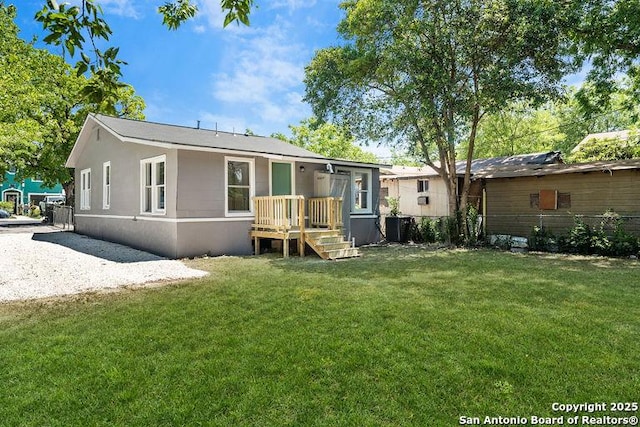 rear view of house featuring a lawn, central AC unit, and fence