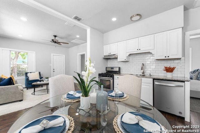 kitchen featuring visible vents, a sink, stainless steel appliances, white cabinetry, and dark wood-type flooring