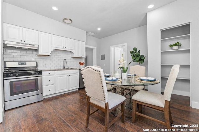 kitchen with under cabinet range hood, white cabinetry, appliances with stainless steel finishes, and a sink