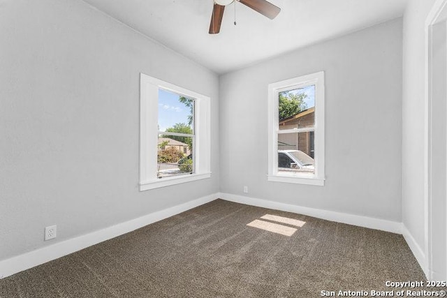 unfurnished room with dark colored carpet, a ceiling fan, and baseboards