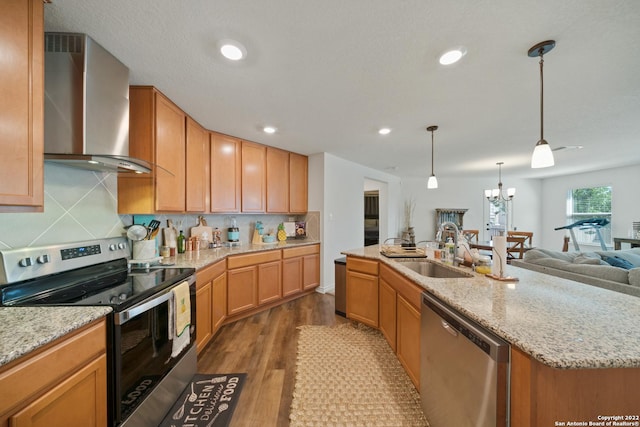kitchen with open floor plan, wall chimney range hood, a sink, dark wood finished floors, and appliances with stainless steel finishes