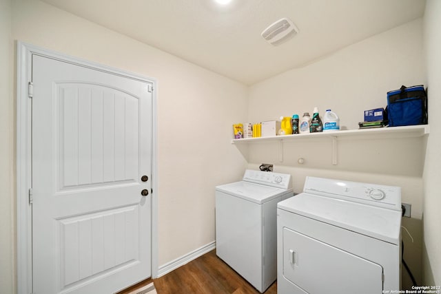 washroom with laundry area, visible vents, washing machine and dryer, baseboards, and dark wood-style floors
