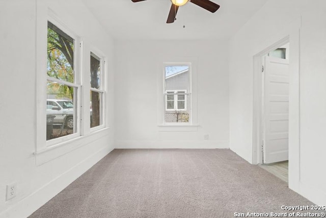 carpeted spare room featuring baseboards and ceiling fan