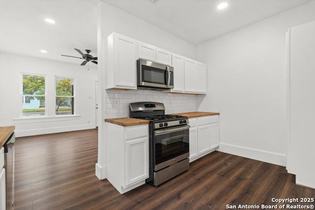 kitchen with dark wood-style flooring, baseboards, appliances with stainless steel finishes, and butcher block counters