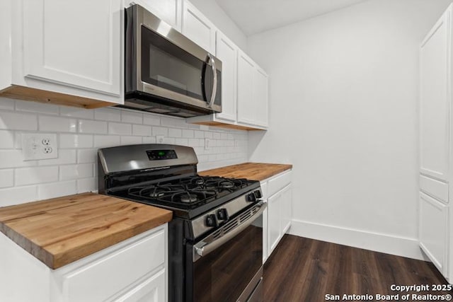 kitchen with decorative backsplash, dark wood-style flooring, butcher block counters, baseboards, and appliances with stainless steel finishes