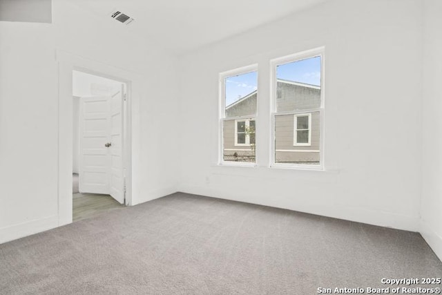 carpeted empty room featuring baseboards and visible vents