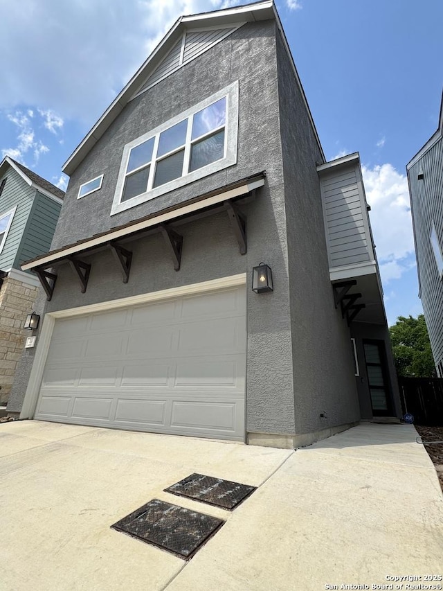 view of front of house featuring concrete driveway, an attached garage, and stucco siding
