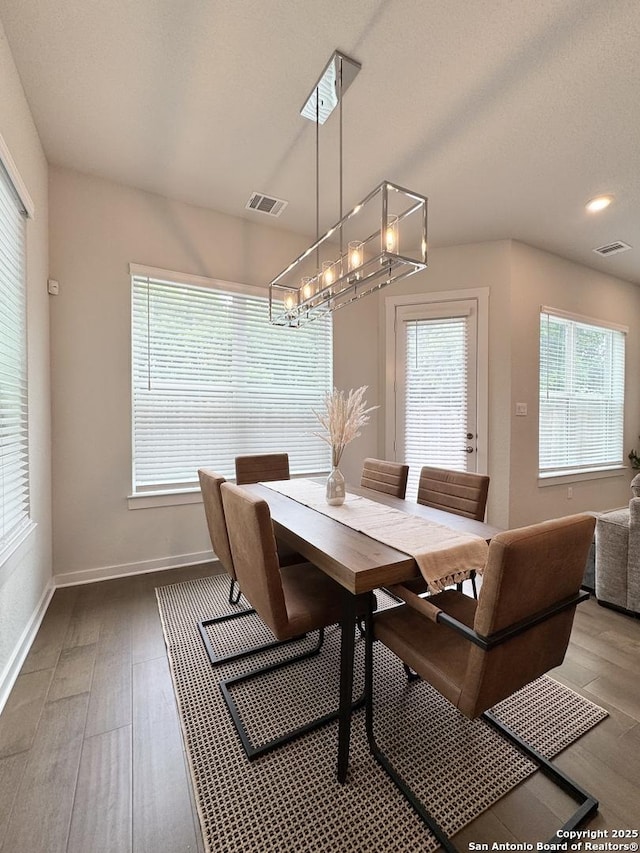 dining space featuring baseboards, an inviting chandelier, wood finished floors, and visible vents