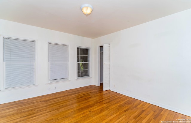 spare room with baseboards and light wood-type flooring