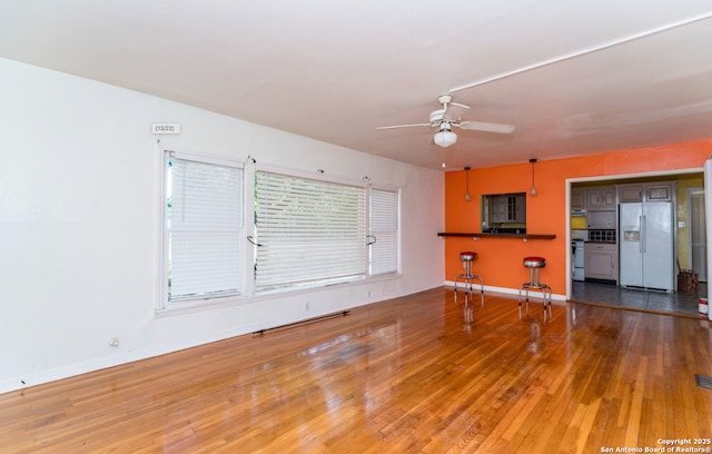 unfurnished living room with a ceiling fan, baseboards, and hardwood / wood-style flooring