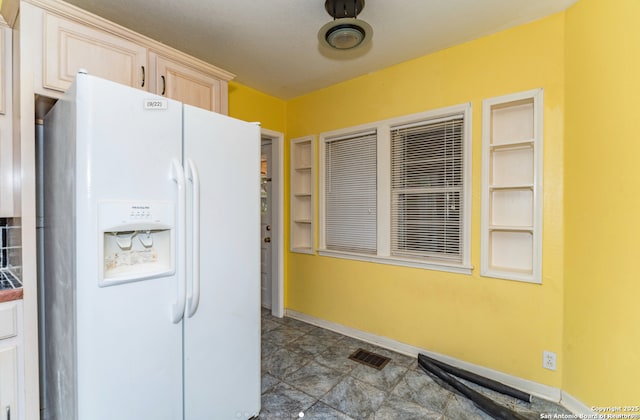 kitchen featuring visible vents, baseboards, light brown cabinetry, and white refrigerator with ice dispenser