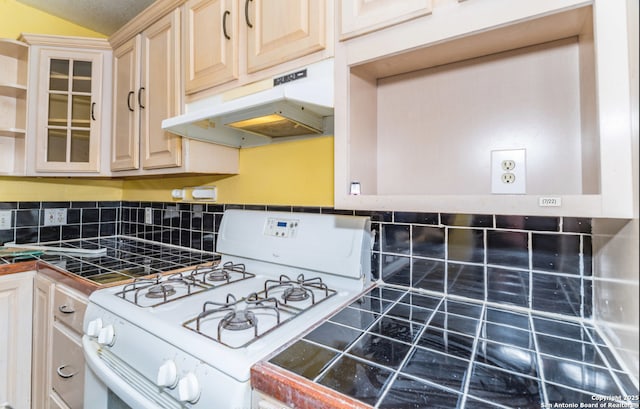 kitchen with open shelves, tile countertops, backsplash, white range with gas stovetop, and under cabinet range hood