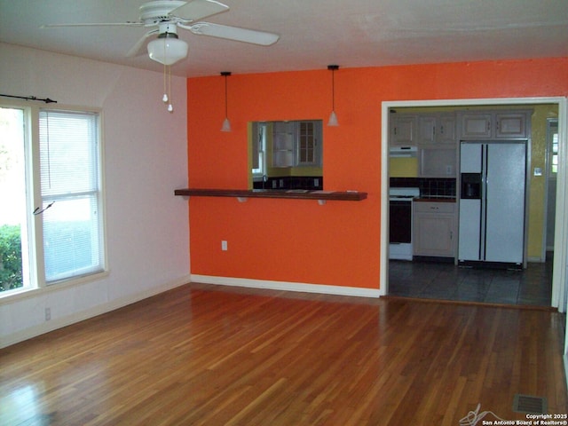 kitchen with white appliances, baseboards, plenty of natural light, and wood finished floors