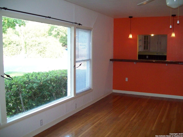 interior space with baseboards, a ceiling fan, and wood finished floors
