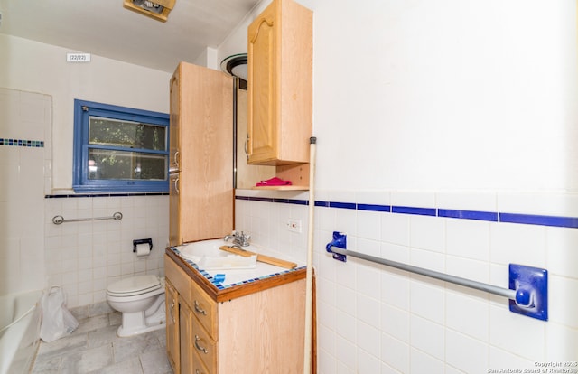 bathroom with vanity, toilet, tile patterned floors, tile walls, and a bath