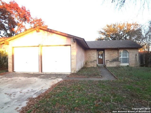 single story home with concrete driveway, brick siding, and a garage