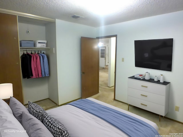 bedroom with a closet, a textured ceiling, visible vents, baseboards, and light carpet
