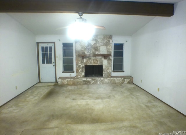 unfurnished living room with a ceiling fan, carpet, a stone fireplace, and beam ceiling